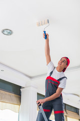 Young painter painting the ceiling in construction concept