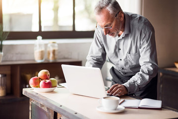 Good-looking enterpreneur working on laptop while having coffee and breakfast