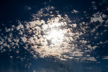 Naklejka na ściany i meble Dark blue sky with sun in clouds