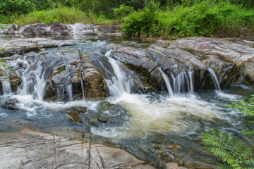 Waterfall flowing over flat rocks in forest.