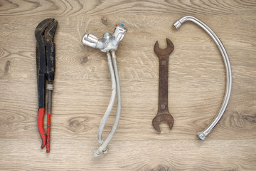 Old plumbing tools and tap on wooden background