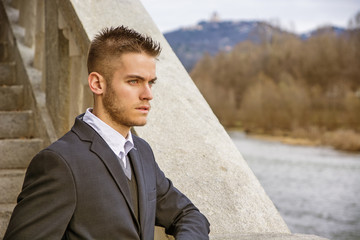 Handsome young man outdoor wearing jacket and shirt standing by historic building in European city. Turin, Italy