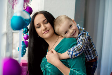 Portrait of happy mother and little son sitting on the farm near the Christmas tree of gifts. The concept of Christmas