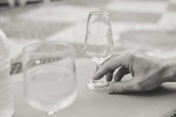 Closeup view of male hand holding a wine glass, table background