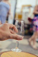 Closeup on human hand holding wine glass, bar restaurant terrace on background