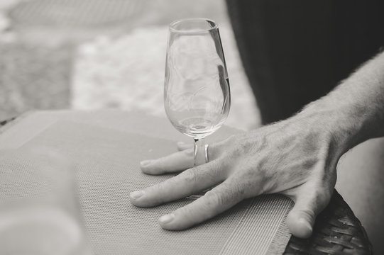 Closeup view of male hand holding a wine glass, table background