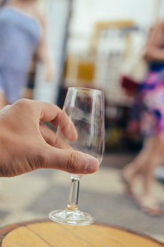 Closeup on human hand holding wine glass, bar restaurant terrace on background