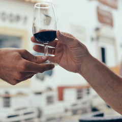 Closeup on person's hand serving holding a glass of wine for tasting.