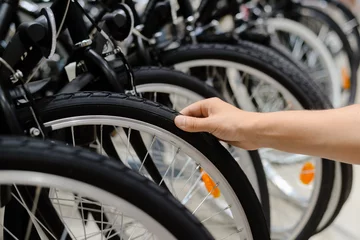 Photo sur Plexiglas Vélo Closeup on person hand checking bicycle tire, shop factory background.