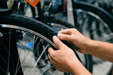 Closeup on person hand checking bicycle tire, shop factory background.