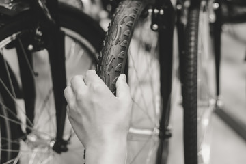 Black and white image close up on human hand checking bicycle tire