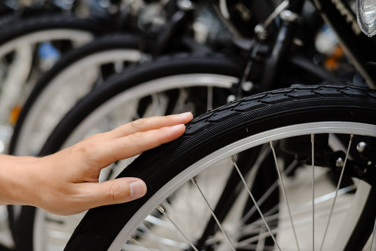Fototapeta Closeup on person hand checking bicycle tire, shop factory background.