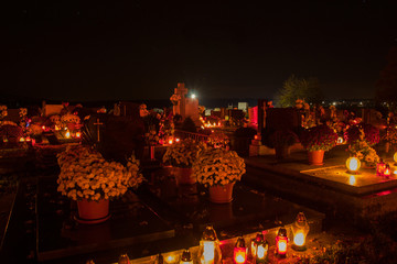 Votive candles lantern burning on the graves in Slovak cemetery at night time. All Saints' Day. Solemnity of All Saints. All Hallows eve. 1st November. Feast of All Saints. Hallowmas. All Souls' Day