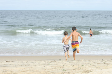 Fototapeta na wymiar Kids running into the ocean at the beach