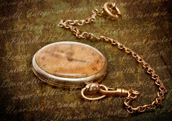 Old clock with chain lying on rough green surface