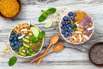 Acai and matcha green tea breakfast superfoods smoothies bowls topped with chia, flax and pumpkin...
