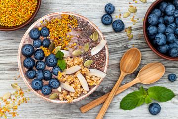 Acai breakfast superfoods smoothies bowl topped with chia, flax and pumpkin seeds, bee pollen,...