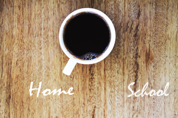 Inscription home and school in a cup of coffee and wooden backgr