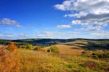 Autumn hills on a sunny day with clouds in the blue sky