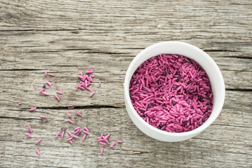 Fototapeta na wymiar Roher rosa Reis auf einem Brett aus Holz