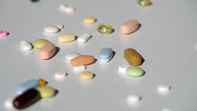 Various types of pills falling on the table
