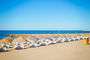 Fototapeta na wymiar Blue sky and straw umbrella on a beautiful tropical beach background
