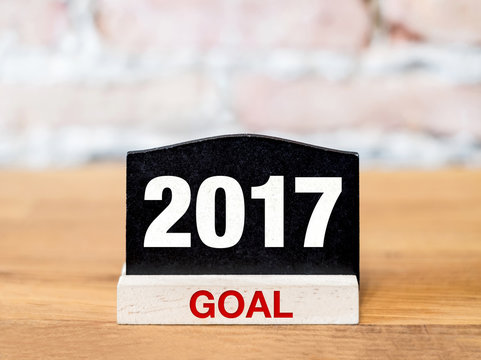 New year 2017 goal on blackboard sign on wood table at brick wal