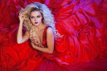 Fashion photo of young magnificent woman in red dress. Studio portrait