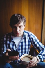 Student using mobile phone while having coffee