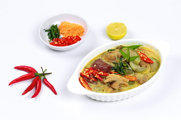 Green chicken curry in coconut milk s with side dish as minced dried shrimp,sliced red chili,sliced kaffir lime leaves and green lemon on white background.