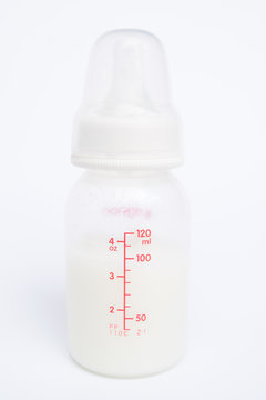 Baby bottle with milk and a measuring scale on white background