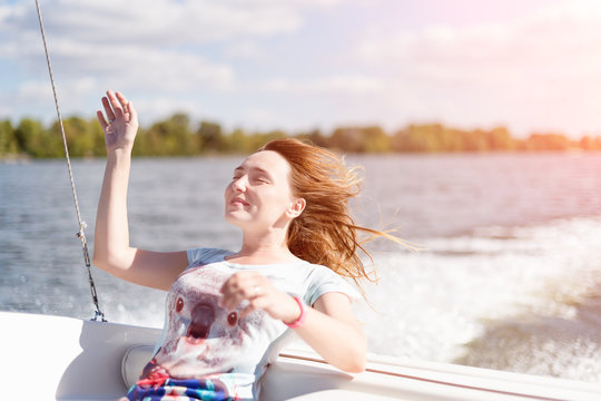 Relaxed young woman with closed eyes of pleasure sitting on sailboat, enjoying mild sunlight, sea or river cruise, summer vacation and travel concept.