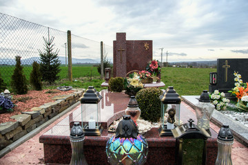 Graves, tombstones and crucifixes on traditional cemetery. Votive candles lantern and flowers on tomb stones in graveyard. All Saints' Day.All Souls' Day. Gravestones in village Tvrdomestice, Slovakia