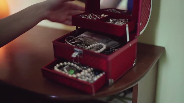 Female hands is opening red box for jewelry, and taken out of the box pearl beads.