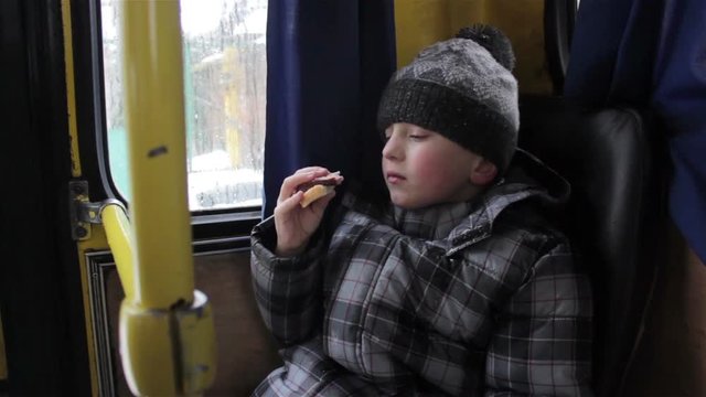 Boy eats in a bus/child boy eat in winter in the middle of the bus