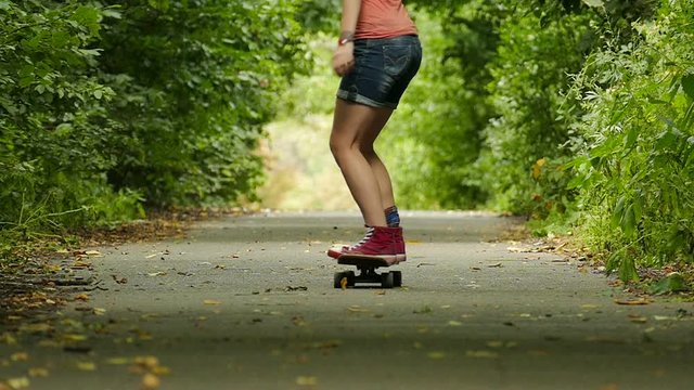 Youth culture . Girl   with  skateboard   jump in  summer park. Slow motion 