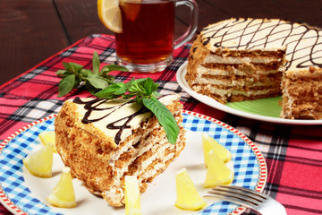 sweet cake with cup of tea end lemon on wooden table