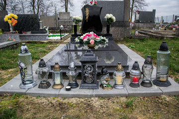 Graves, tombstones and crucifixes on traditional cemetery. Votive candles lantern and flowers on tomb stones in graveyard. All Saints' Day.All Souls' Day. Gravestones in village Tvrdomestice, Slovakia