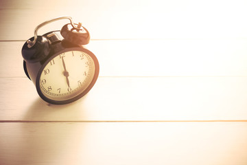Retro Alarm Clock on Wooden Background with Sunlight Thru the Window 6 O'Clock in the Morning
