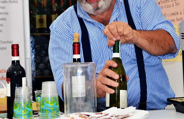 un uomo stappa una bottiglia di vino