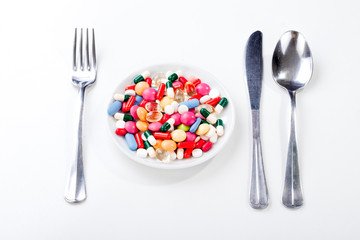 Drugs, medicine on a dish with fork, spoon,knife and sign stop