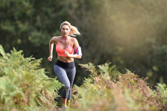 Beautiful athletic woman running in forest