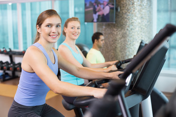 Smiling young people training on exercise machines