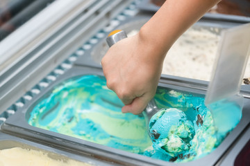 Photo of a metal scoop digging into a tub of  ice cream.
