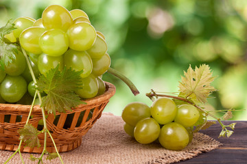 green grapes in a wicker basket on wooden table with blurred background