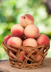 peaches in a wicker basket on wooden table with blurred background