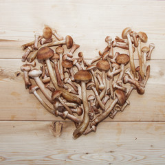 honey agaric mushrooms in shape of heart on wooden background