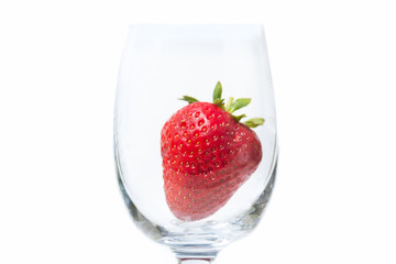 Red and ripe strawberry in wineglass on a white background