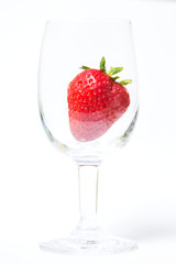 Red and ripe strawberry in wineglass on a white background