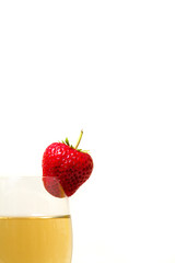 Red and ripe strawberry on glass with a yellow drink
